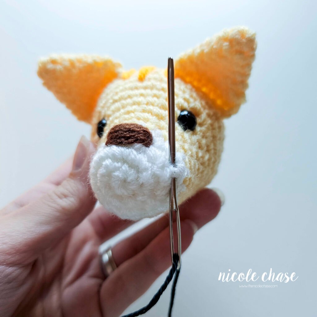 Attaching whiskers to the side of the cat's head.