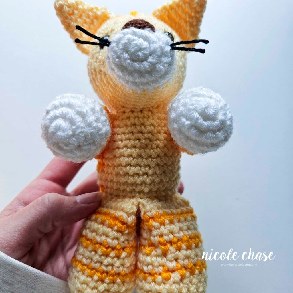 A view of the cat's arms sewn into place at its sides. 