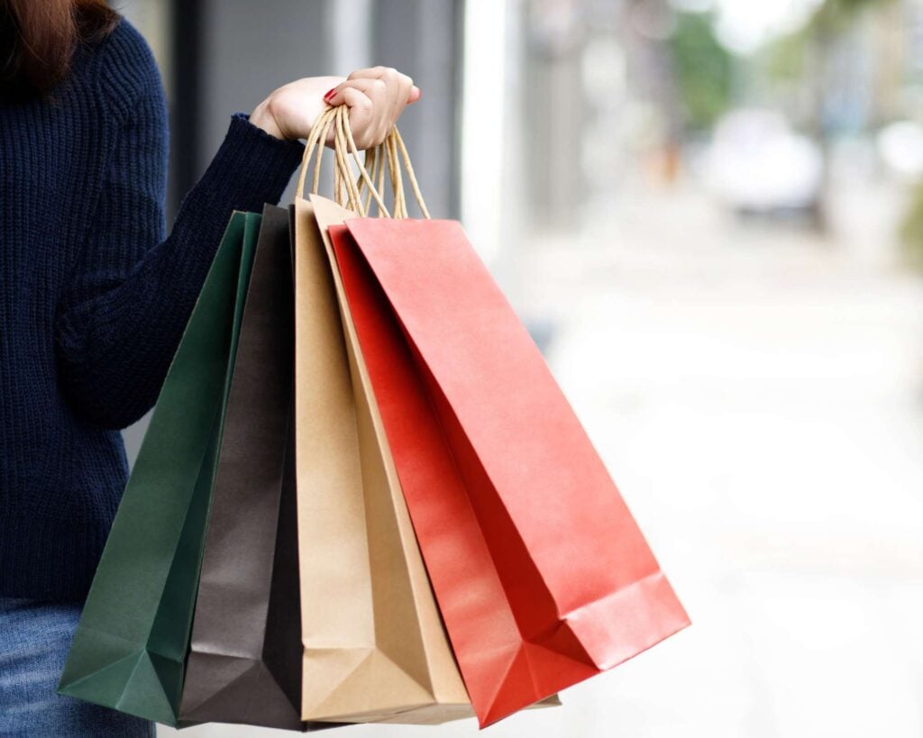 A customer holding multiple shopping bags, representing a successful sales event. 