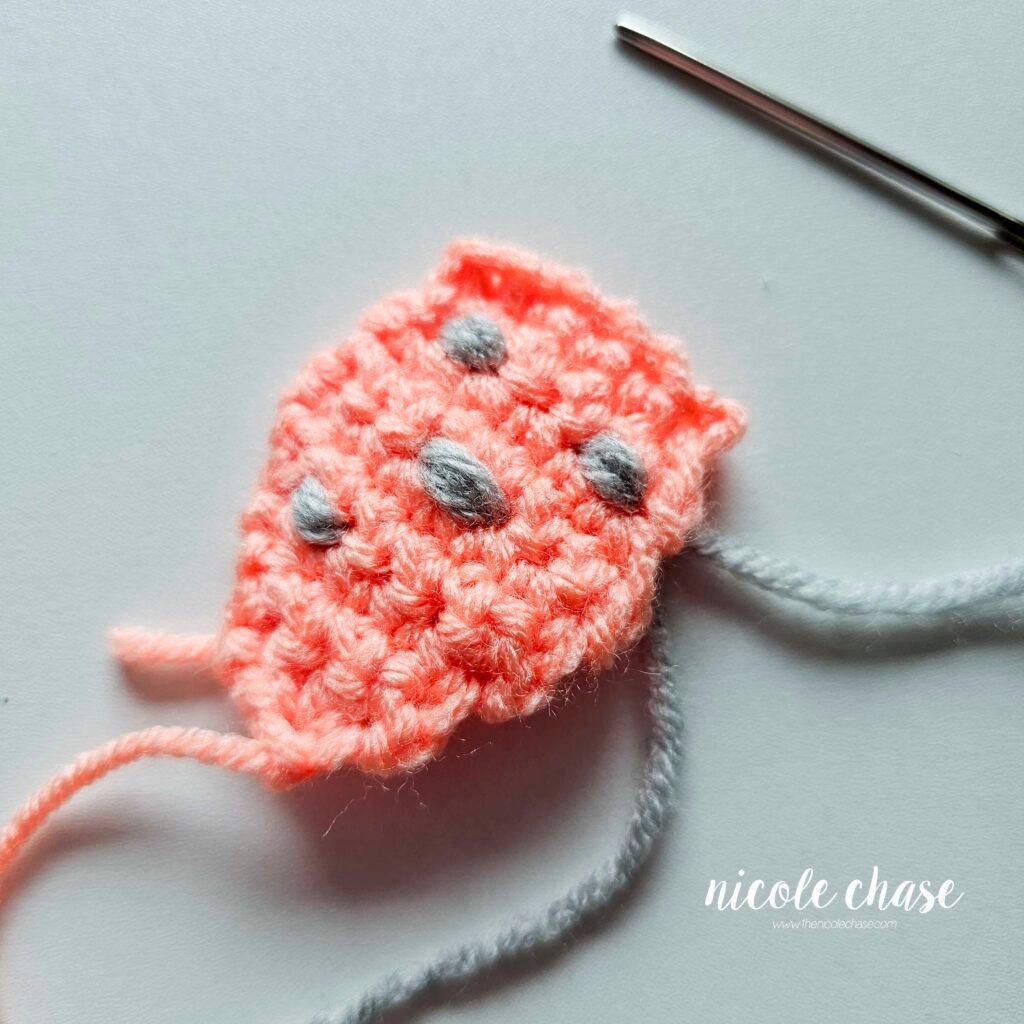 Embroidering the bumps on the back plate of the crochet ankylosaurus, step 8.