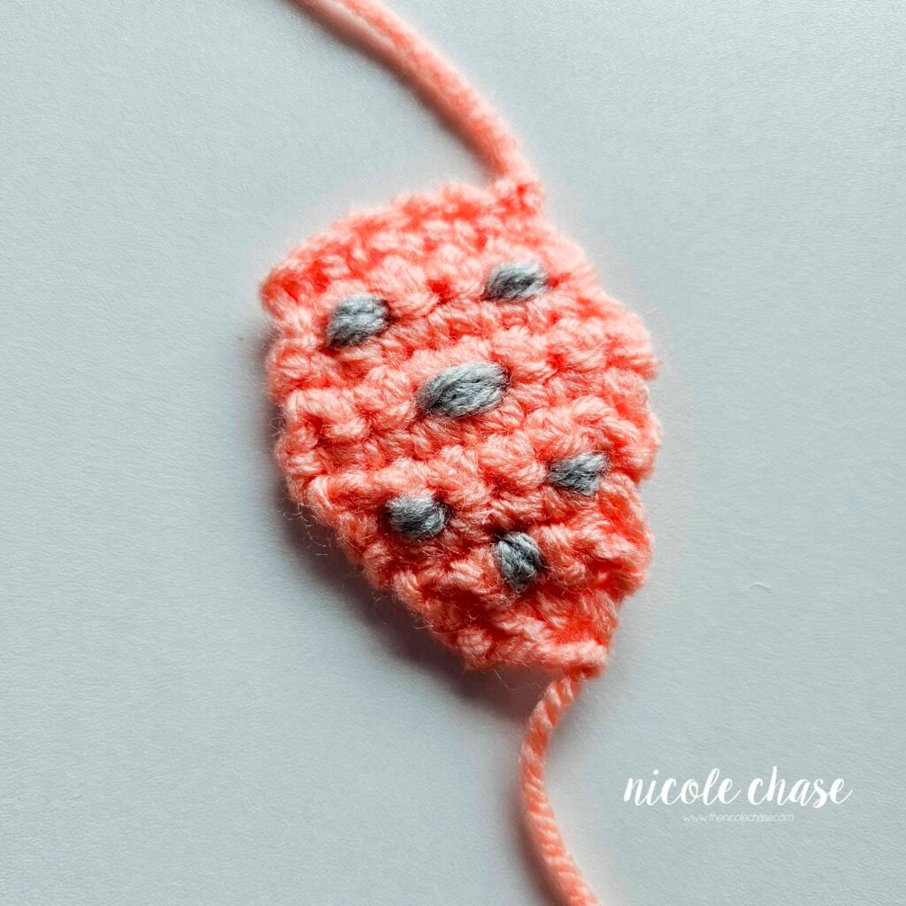 Embroidering the bumps on the back plate of the crochet ankylosaurus, step 11.