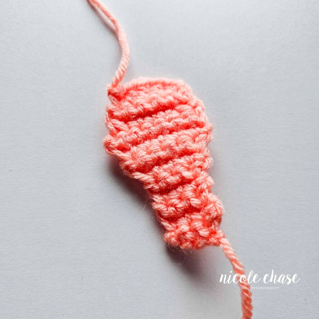 Finished head plate piece of the free small dinosaur crochet pattern for Mini Archie the Ankylosaurus.
