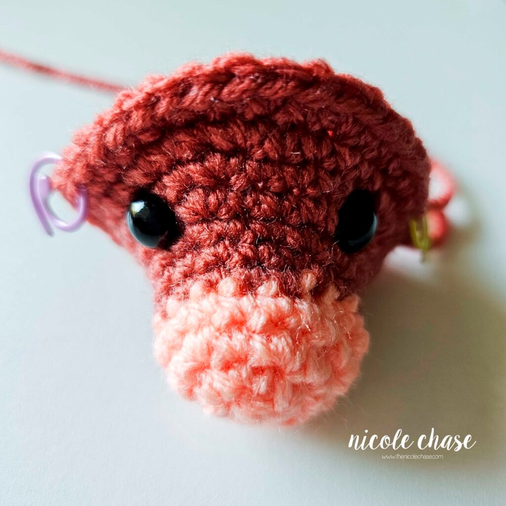 Crochet head of ankylosaurus amigurumi with the safety eyes placed after R11.
