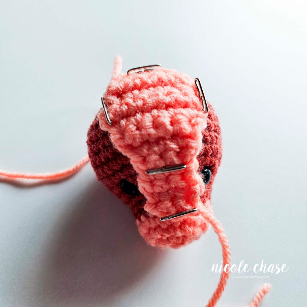 Head plate of the ankylosaurus amigurumi pinned to the head before sewing.