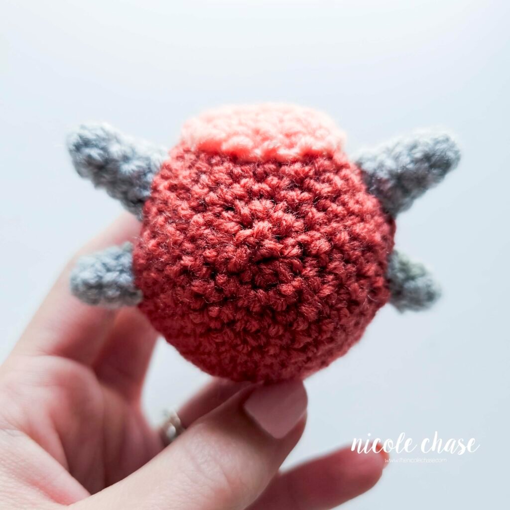 Small spikes of the small dinosaur crochet patterns free sewn into place on the head of Mini Archie, view 3.