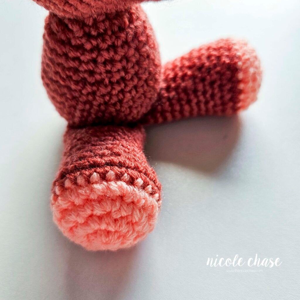 Mini dinosaur crochet pattern free with the legs sewn into place, view 1.