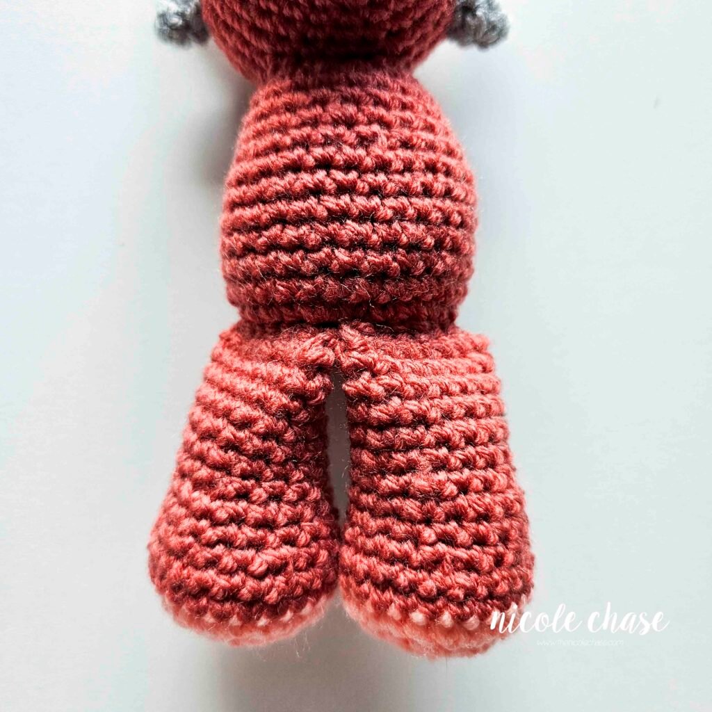 Mini dinosaur crochet pattern free with the legs sewn into place, view 2.