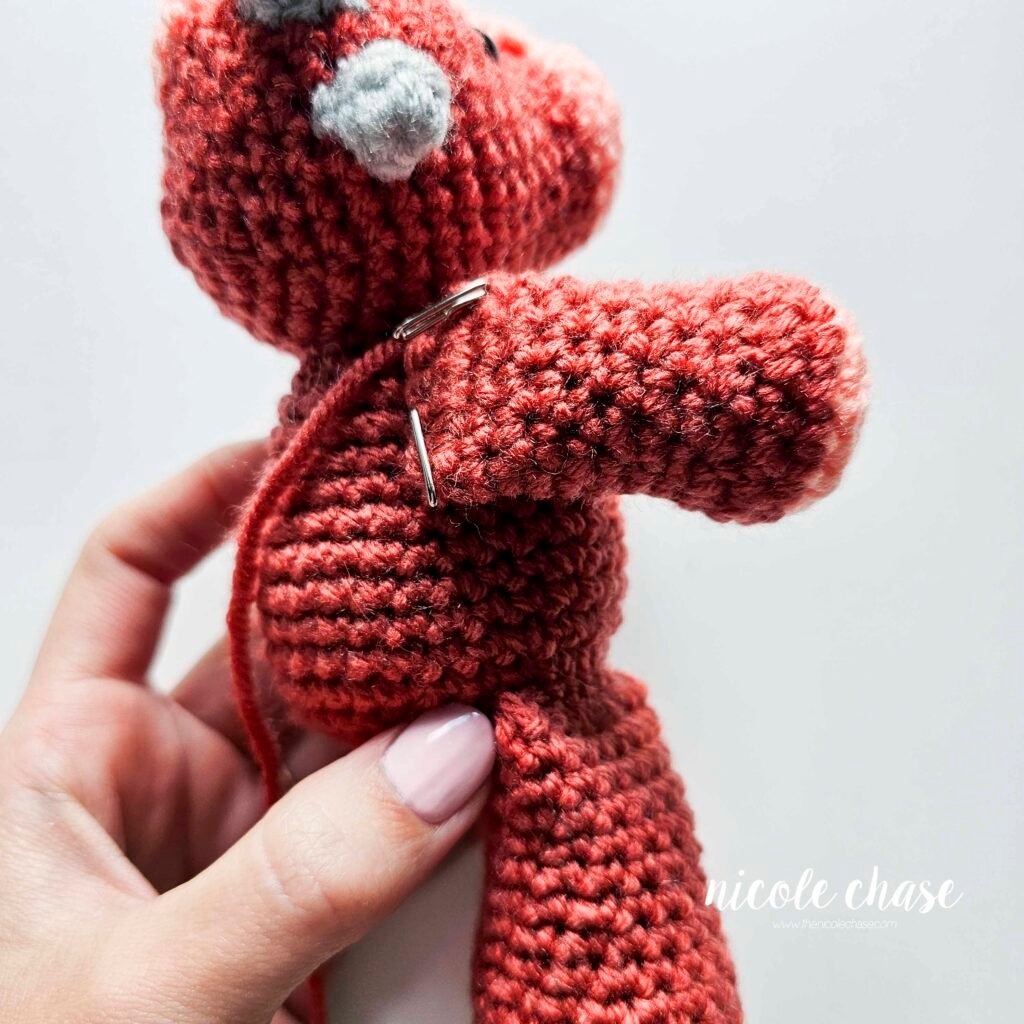 Arms of the ankylosaurus amigurumi pattern held into place with pins to the body piece.