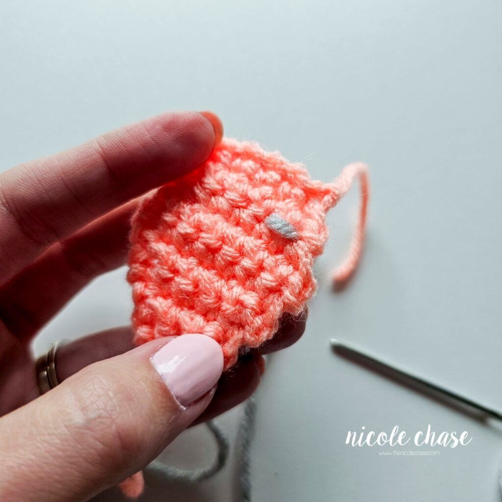 Embroidering the bumps on the back plate of the crochet ankylosaurus, step 3.