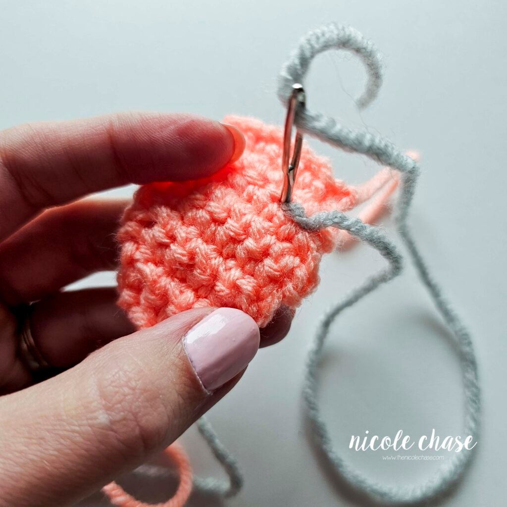 Embroidering the bumps on the back plate of the crochet ankylosaurus, step 4.