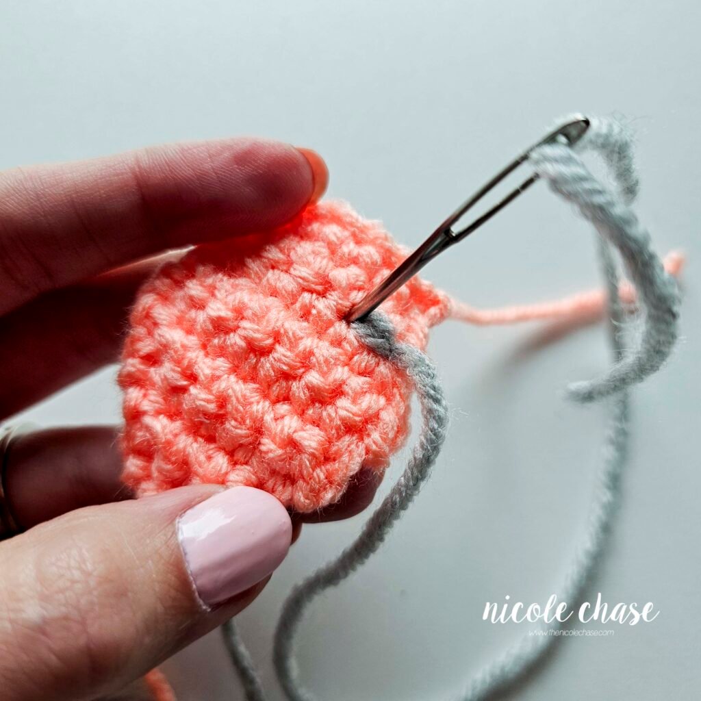 Embroidering the bumps on the back plate of the crochet ankylosaurus, step 5.