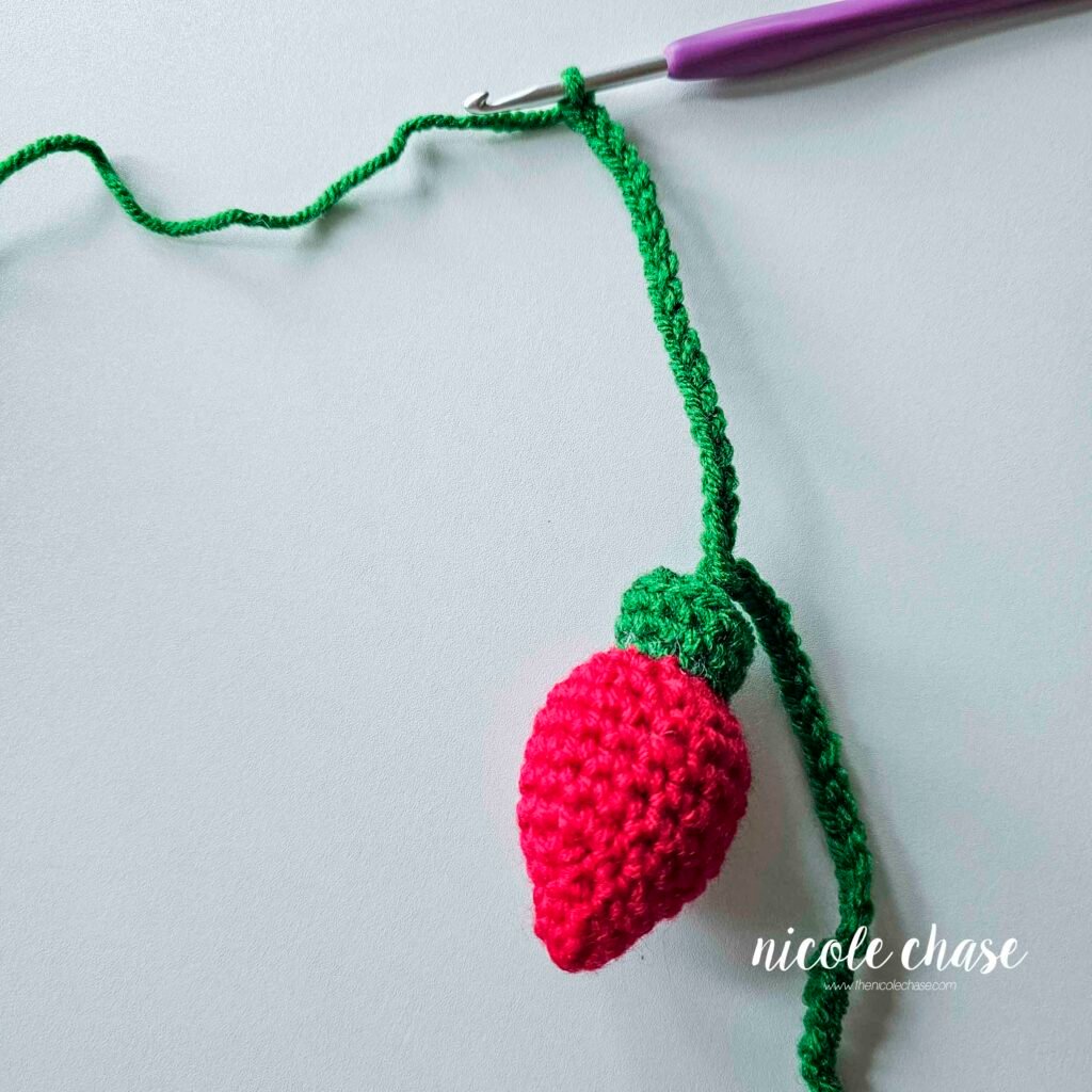 Continuing the green wire for the holiday light crochet pattern, prior to attaching the next light. 