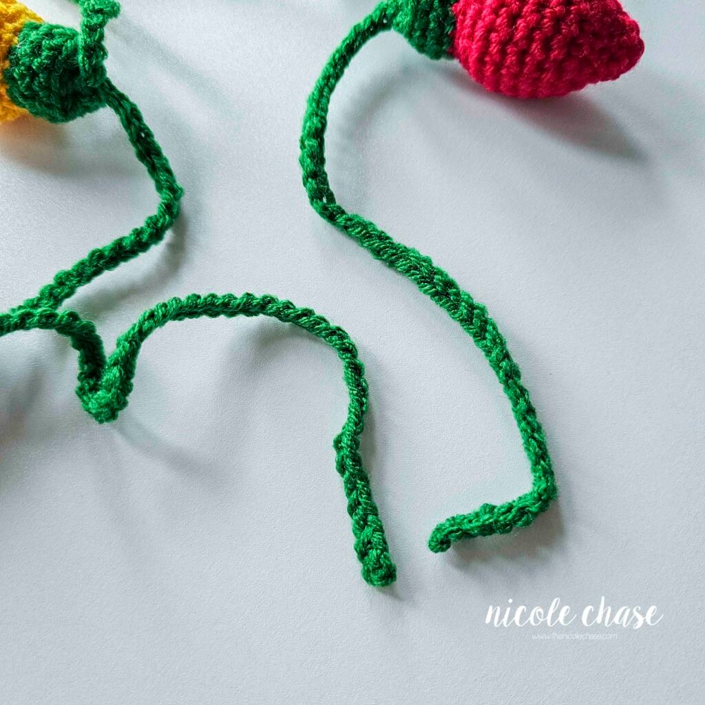 The yarn tails have been weaved into the chain of the holiday lights crochet pattern garland. 