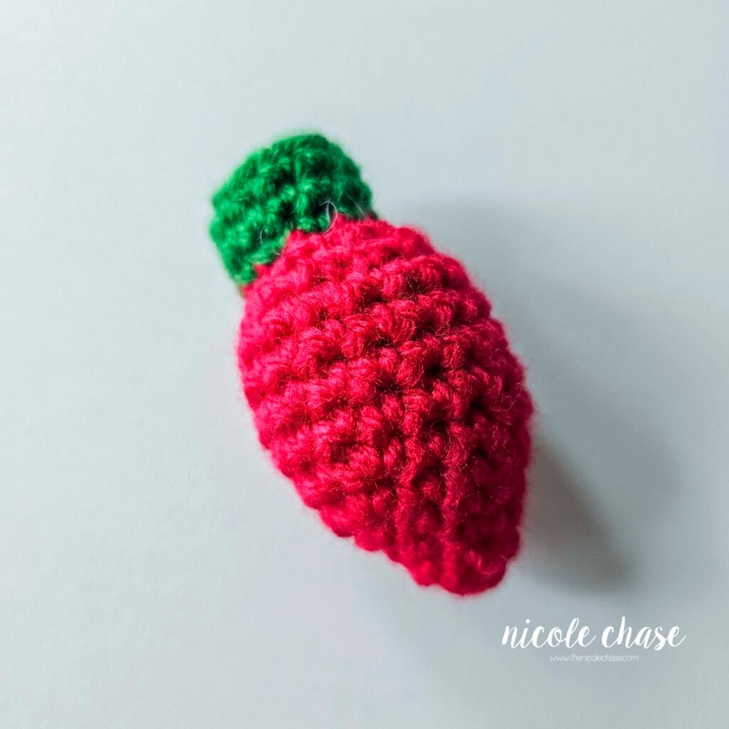 The finished crochet Christmas light made in red yarn with a green base. 