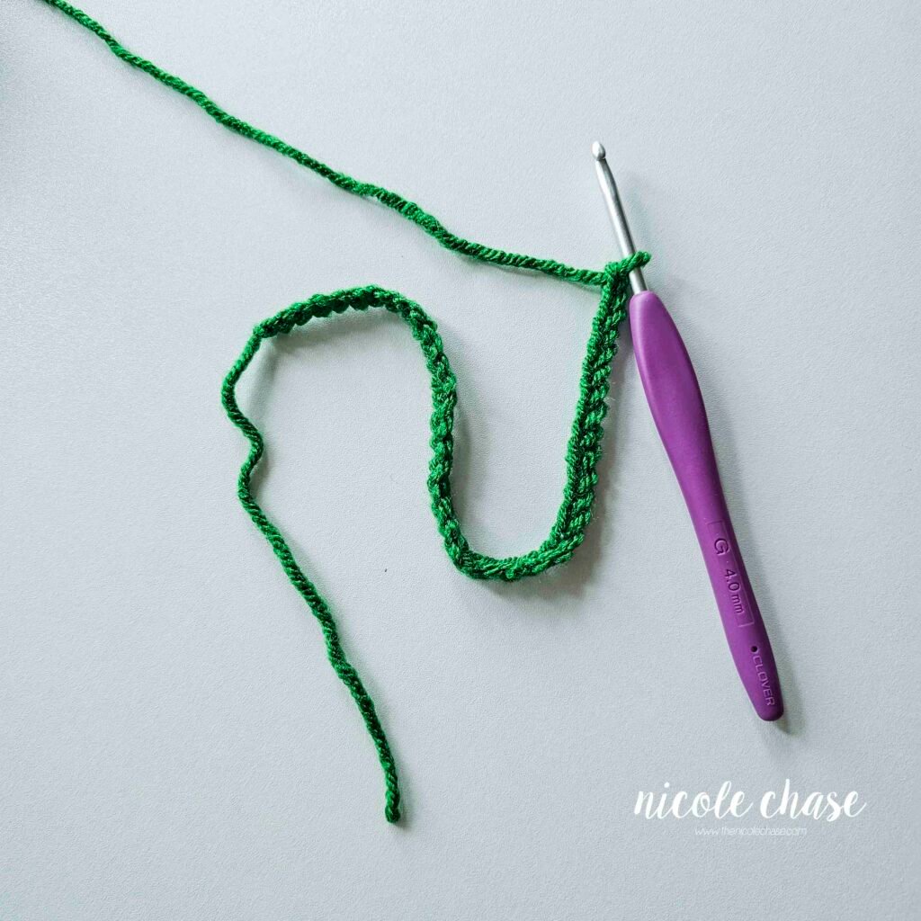 The start of the wire for the string of crochet Christmas lights, showing a long chain of stitches in the green yarn. 