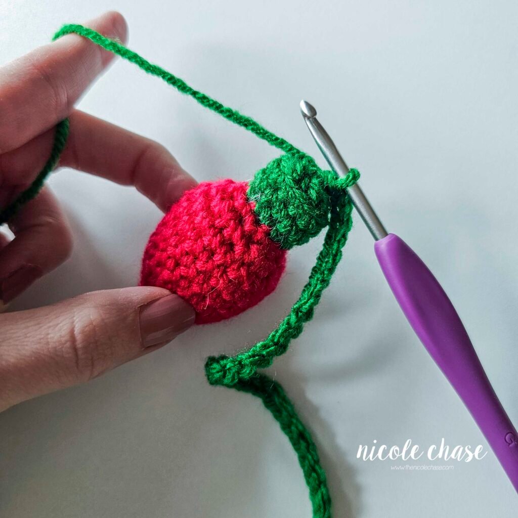 Connecting the green chain to the top of the first crochet holiday light, step 3.