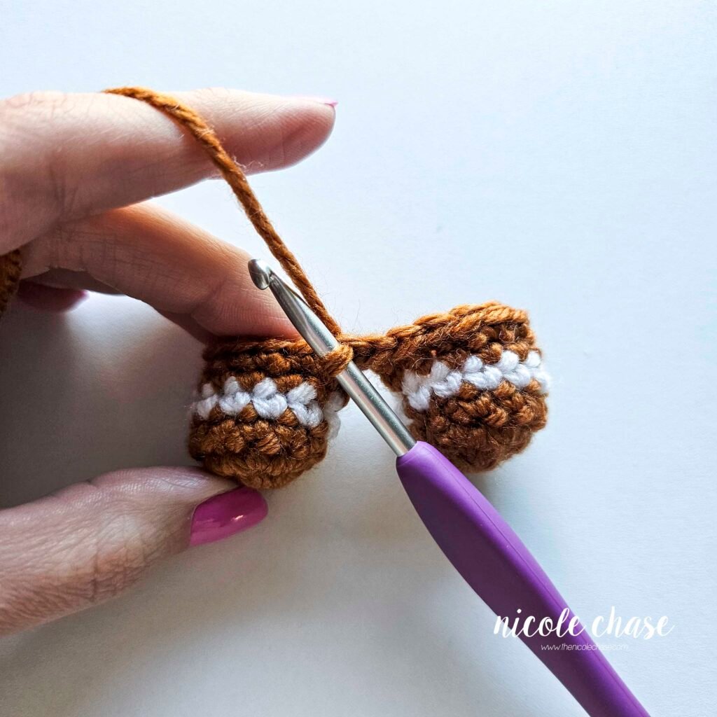 Tutorial photo showing the method for joining the two crocheted legs together at the start of the nearly no-sew crochet gingerbread man pattern, step 9.