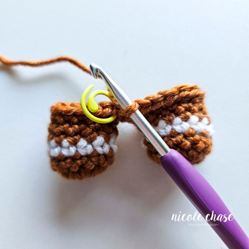 Tutorial photo showing the method for joining the two crocheted legs together at the start of the nearly no-sew crochet gingerbread man pattern, step 10.