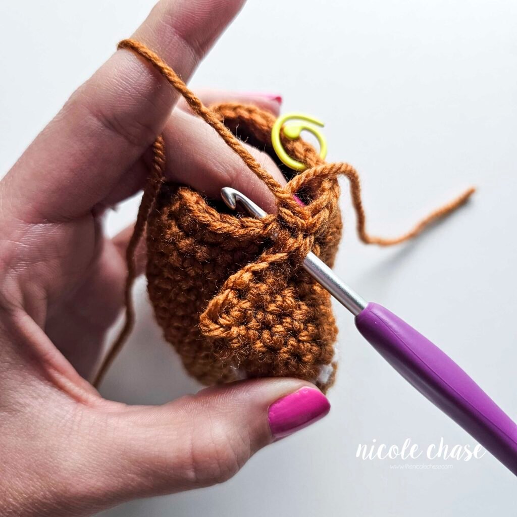 Tutorial photo showing the method for attaching the two crocheted arms at R20 of the nearly no-sew crochet gingerbread man pattern, step 2.