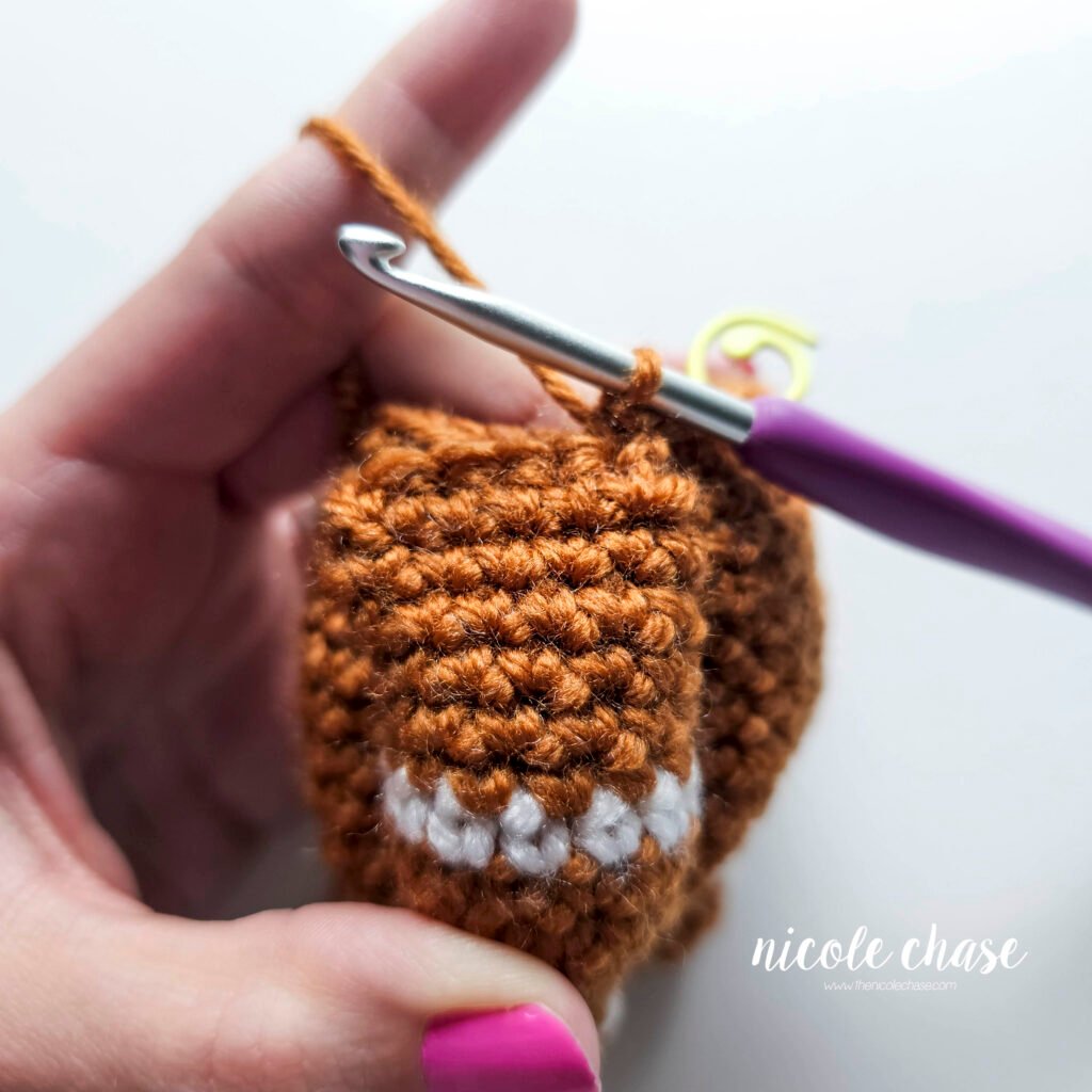 Tutorial photo showing the method for attaching the two crocheted arms at R20 of the nearly no-sew crochet gingerbread man pattern, step 3.