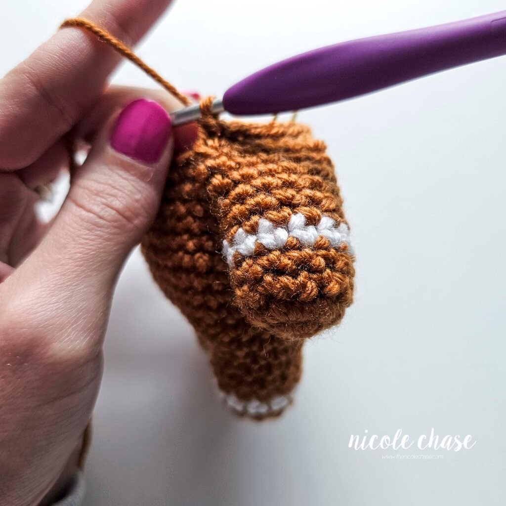 Tutorial photo showing the method for attaching the two crocheted arms at R20 of the nearly no-sew crochet gingerbread man pattern, step 4.