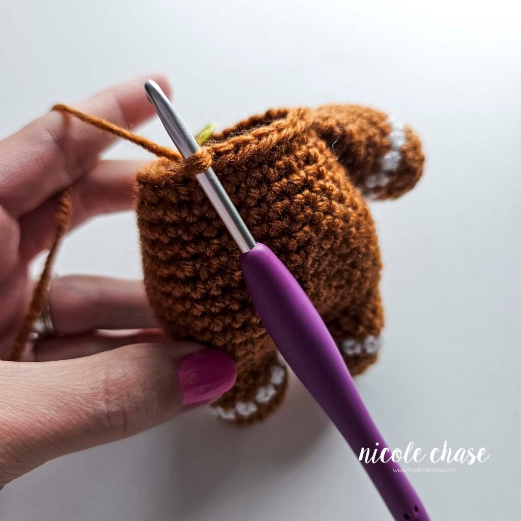 Tutorial photo showing the method for attaching the two crocheted arms at R20 of the nearly no-sew crochet gingerbread man pattern, step 5.