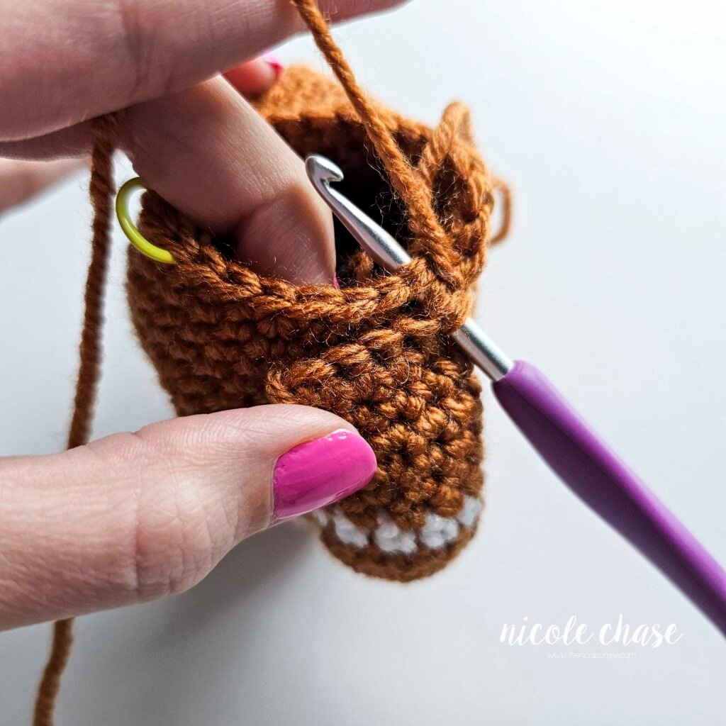 Tutorial photo showing the method for attaching the two crocheted arms at R20 of the nearly no-sew crochet gingerbread man pattern, step 6.