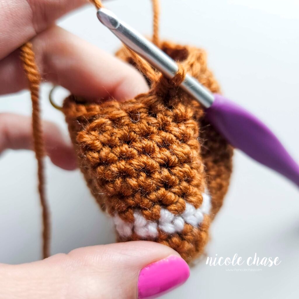 Tutorial photo showing the method for attaching the two crocheted arms at R20 of the nearly no-sew crochet gingerbread man pattern, step 7.