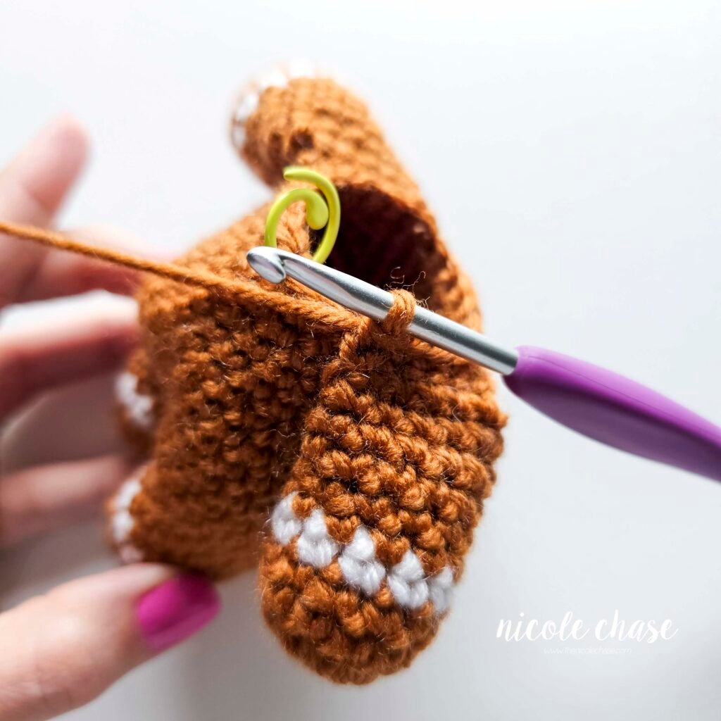 Tutorial photo showing the method for attaching the two crocheted arms at R20 of the nearly no-sew crochet gingerbread man pattern, step 8.