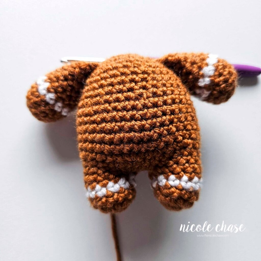 Tutorial photo showing the method for attaching the two crocheted arms at R20 of the nearly no-sew crochet gingerbread man pattern, step 10.