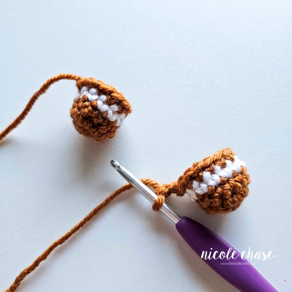 Tutorial photo showing the method for joining the two crocheted legs together at the start of the nearly no-sew crochet gingerbread man pattern, step 2.