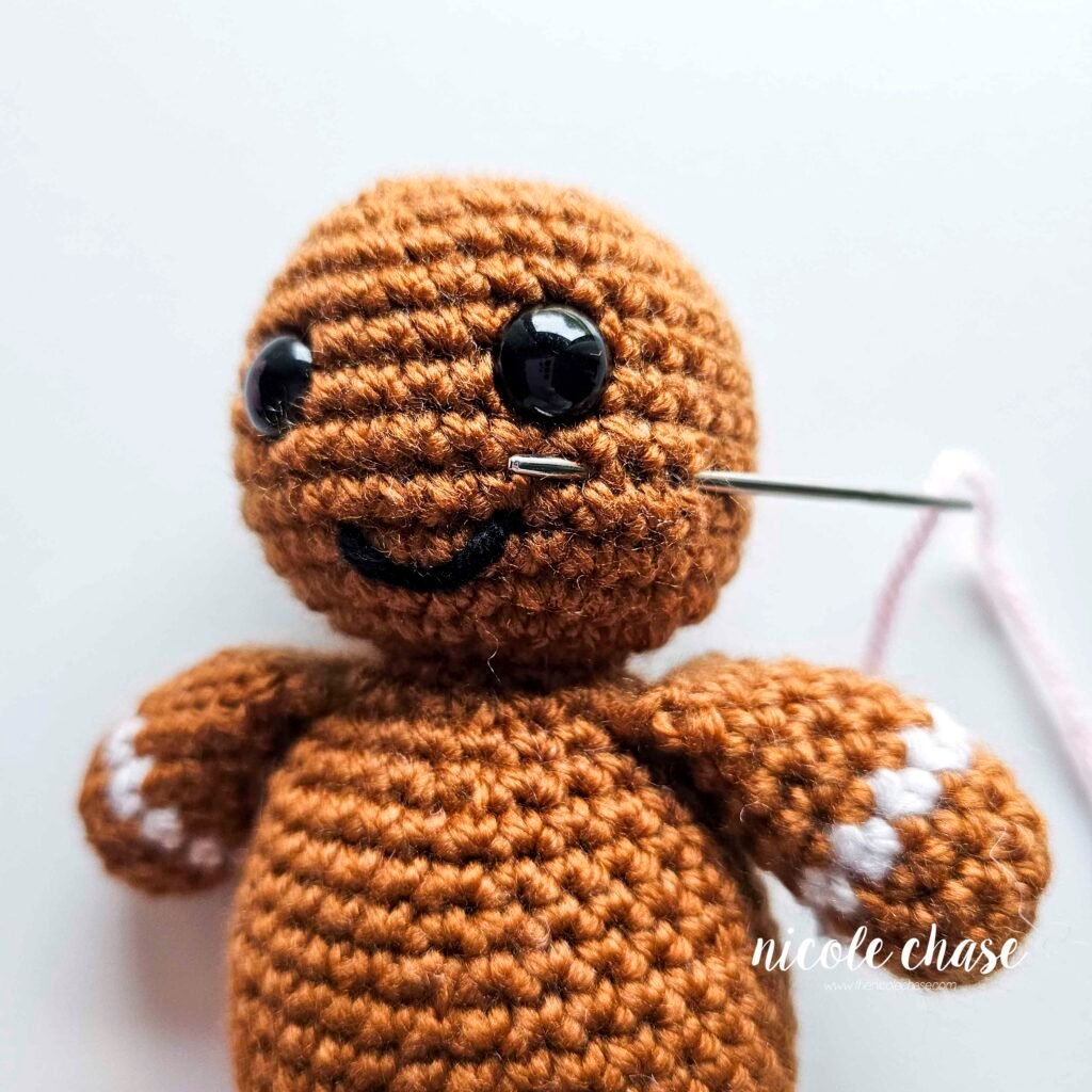 Embroidering blush on the head of the free gingerbread crochet pattern, step 1.