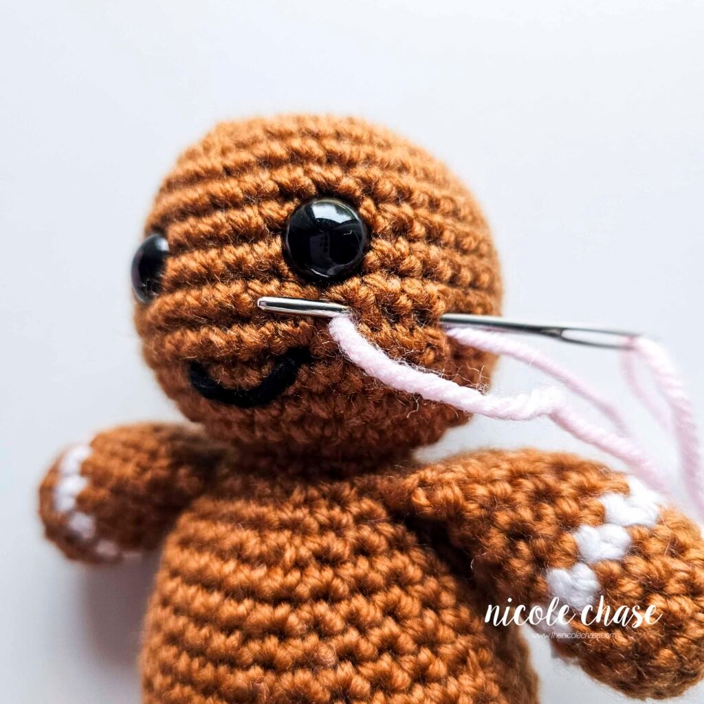 Embroidering blush on the head of the free gingerbread crochet pattern, step 2.