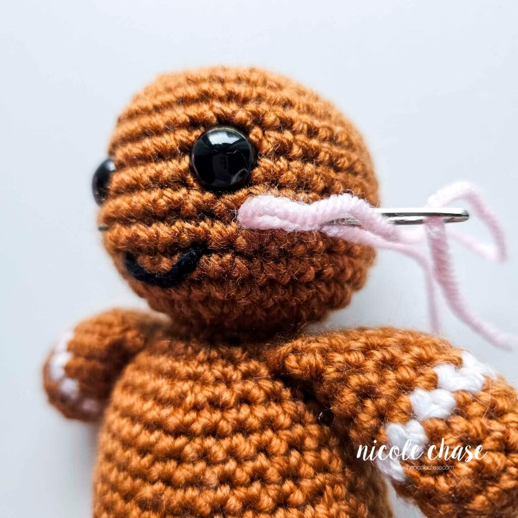 Embroidering blush on the head of the free gingerbread crochet pattern, step 3.