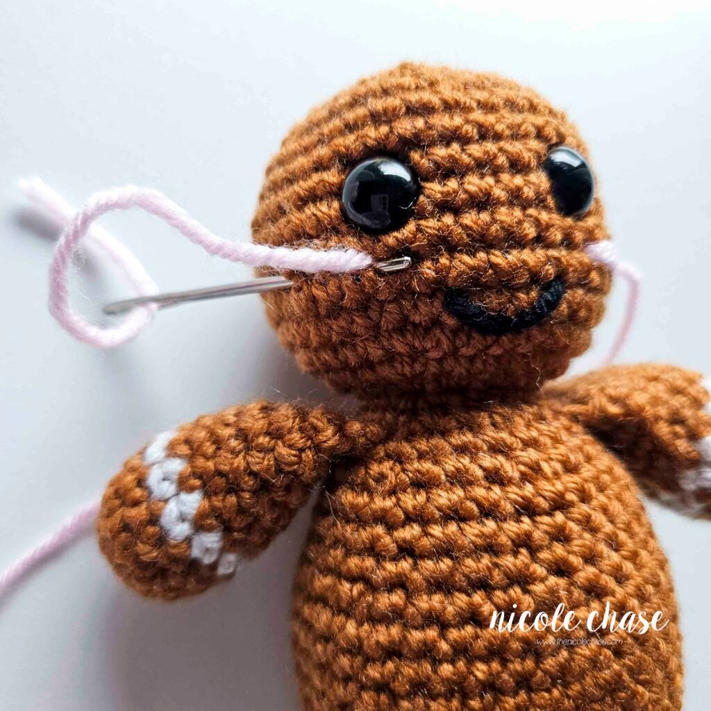 Embroidering blush on the head of the free gingerbread crochet pattern, step 4.