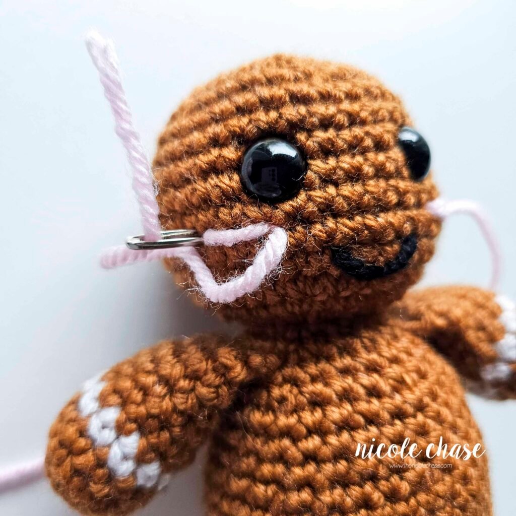 Embroidering blush on the head of the free gingerbread crochet pattern, step 5.