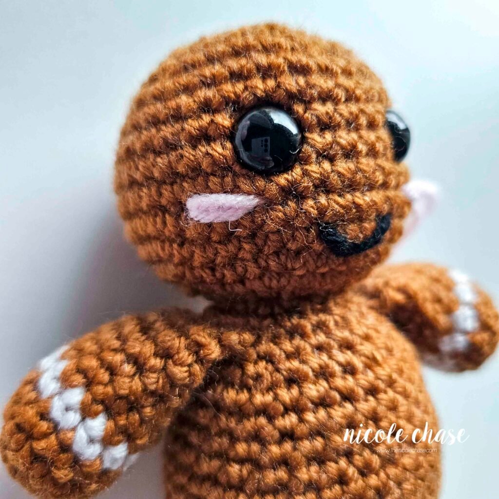 Embroidering blush on the head of the free gingerbread crochet pattern, step 6.