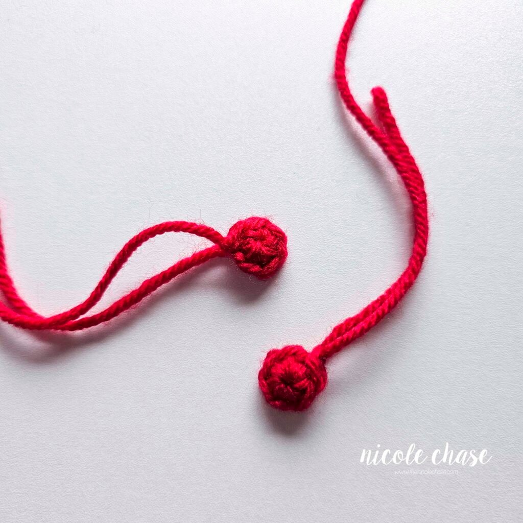 Two red buttons to be attached to the belly of the crochet gingerbread pattern. 