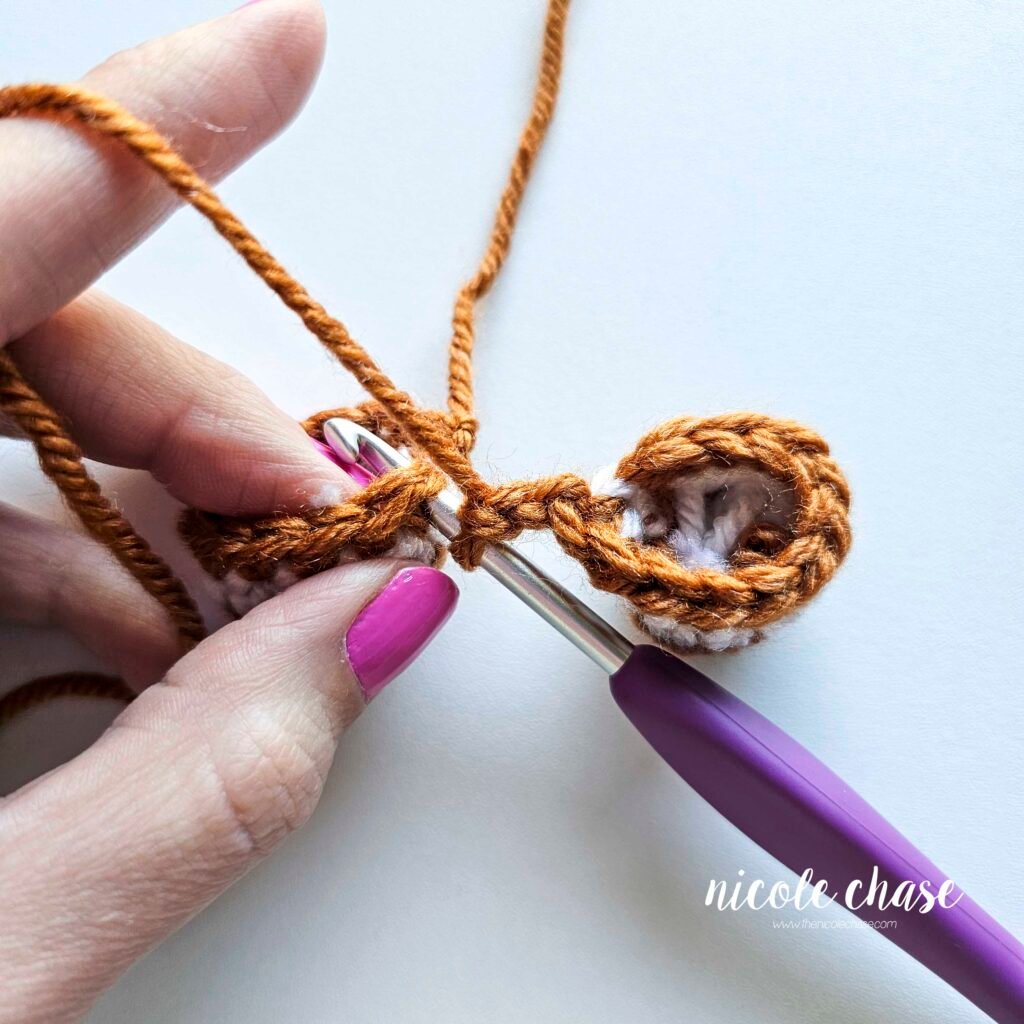 Tutorial photo showing the method for joining the two crocheted legs together at the start of the nearly no-sew crochet gingerbread man pattern, step 3.
