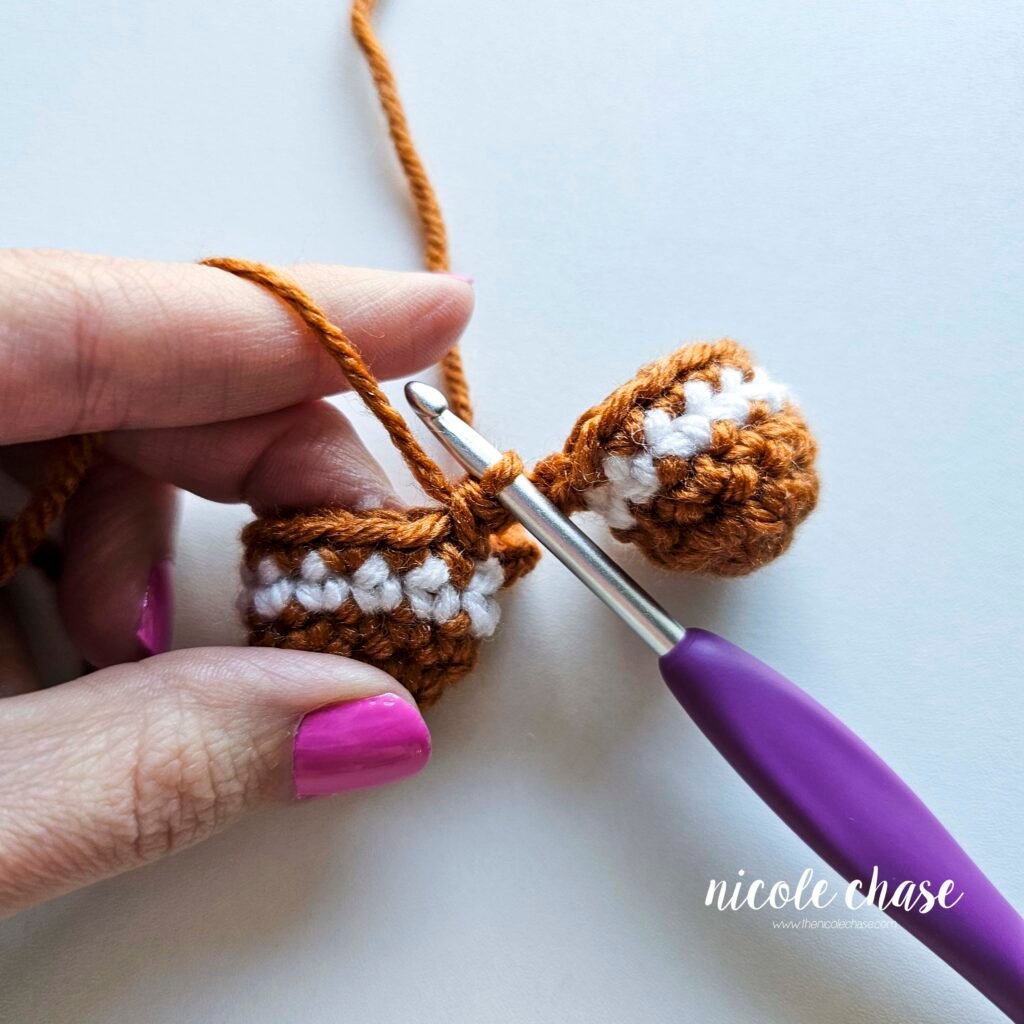 Tutorial photo showing the method for joining the two crocheted legs together at the start of the nearly no-sew crochet gingerbread man pattern, step 4.