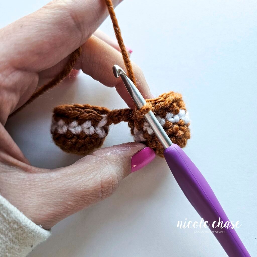 Tutorial photo showing the method for joining the two crocheted legs together at the start of the nearly no-sew crochet gingerbread man pattern, step 5.