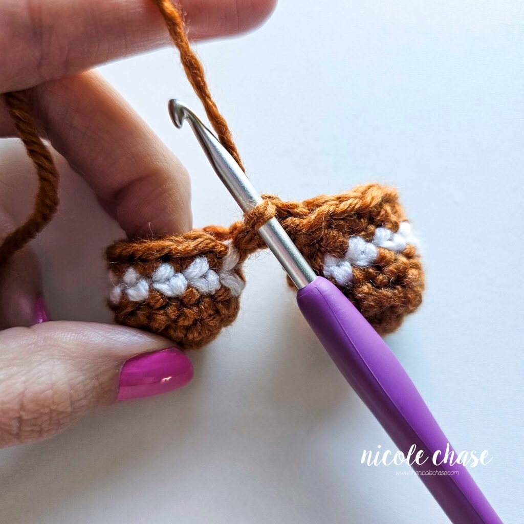 Tutorial photo showing the method for joining the two crocheted legs together at the start of the nearly no-sew crochet gingerbread man pattern, step 6.