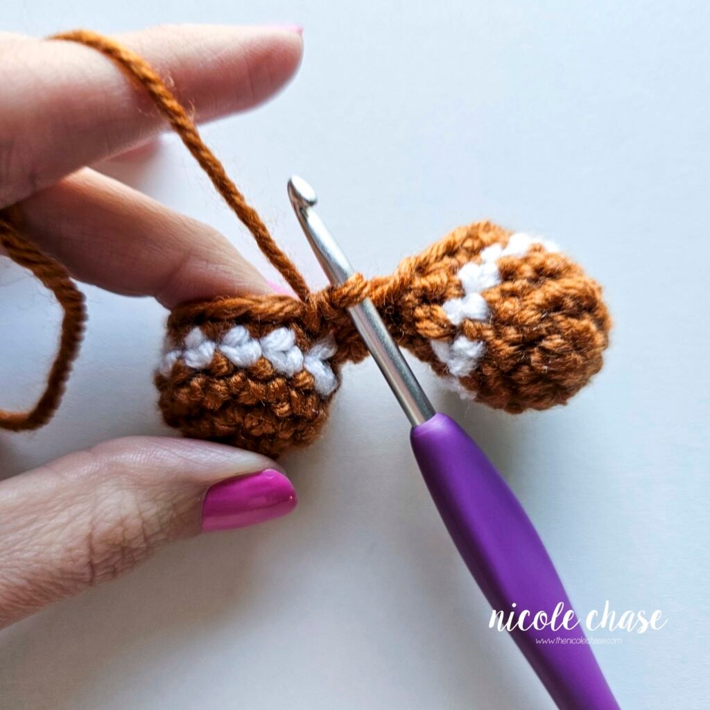 Tutorial photo showing the method for joining the two crocheted legs together at the start of the nearly no-sew crochet gingerbread man pattern, step 7.