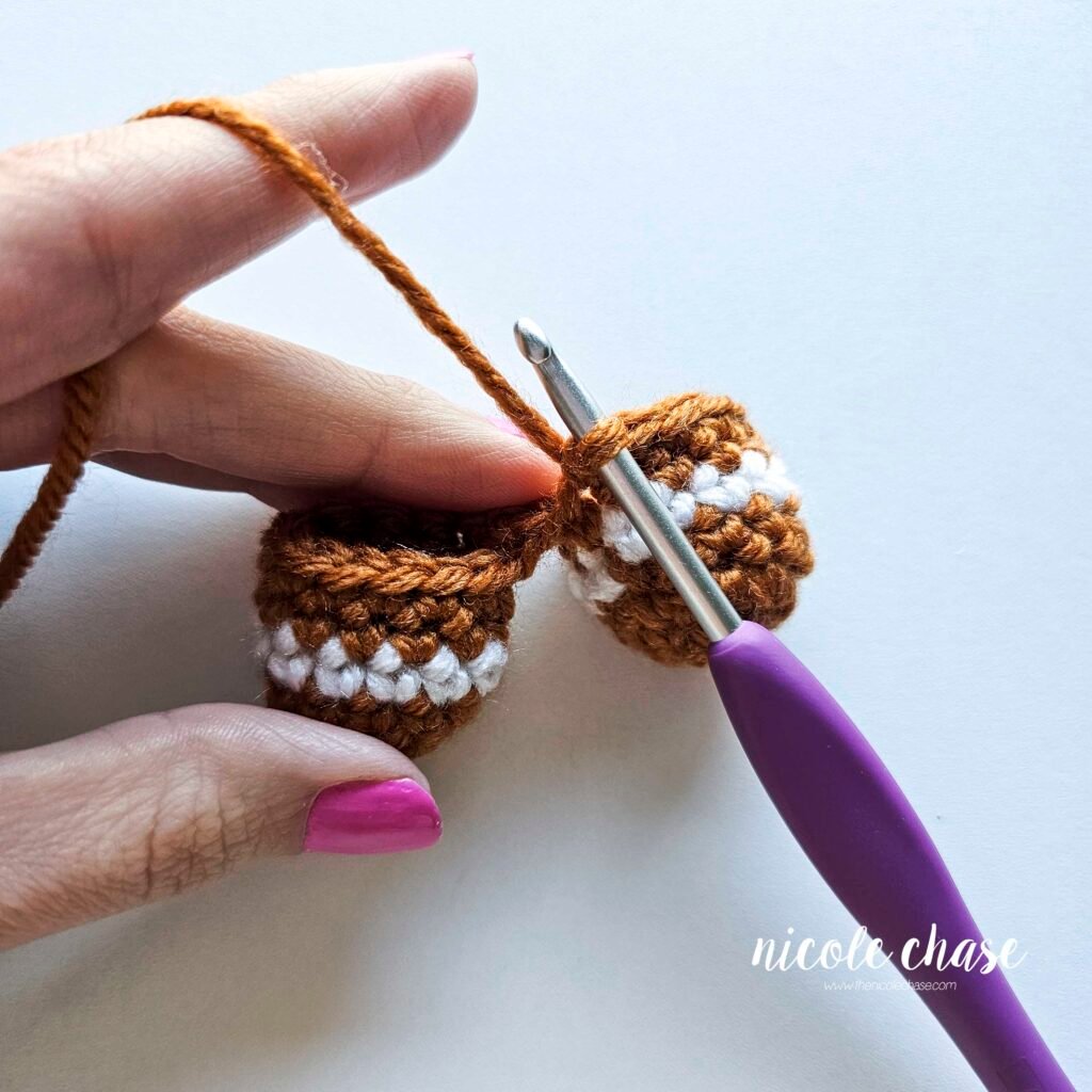 Tutorial photo showing the method for joining the two crocheted legs together at the start of the nearly no-sew crochet gingerbread man pattern, step 8.