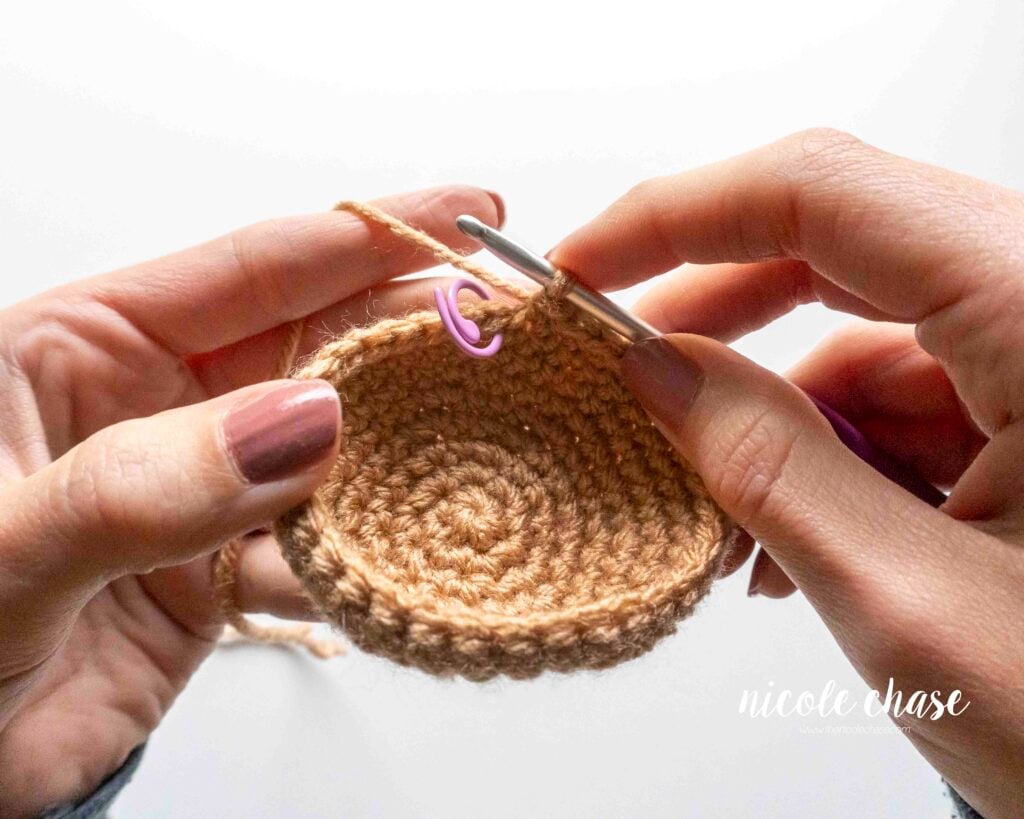 Step-by-step tutorial showing how to flip a larger, more structured amigurumi piece inside out when realizing the wrong side is facing out in later rounds, step 1.