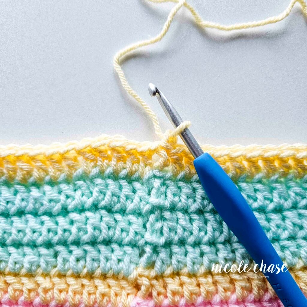 Crocheting the single crochet edging around the blanket of the crochet lion lovey pattern, step 1.