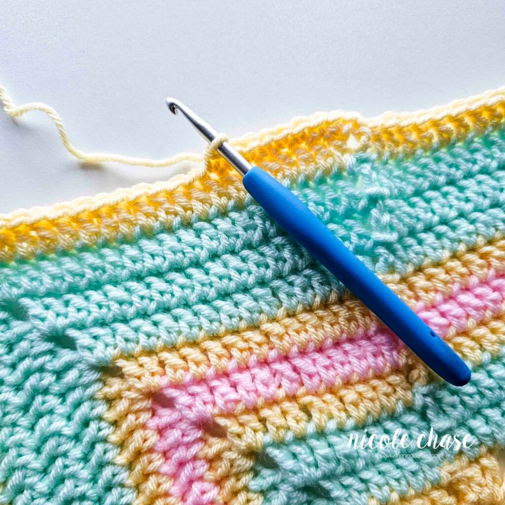 Crocheting the single crochet edging around the blanket of the crochet lion lovey pattern, step 2.