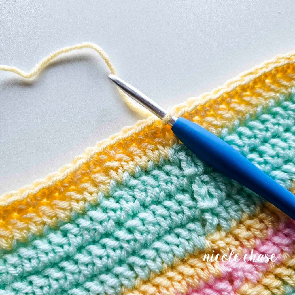 Crocheting the single crochet edging around the blanket of the crochet lion lovey pattern, step 5.