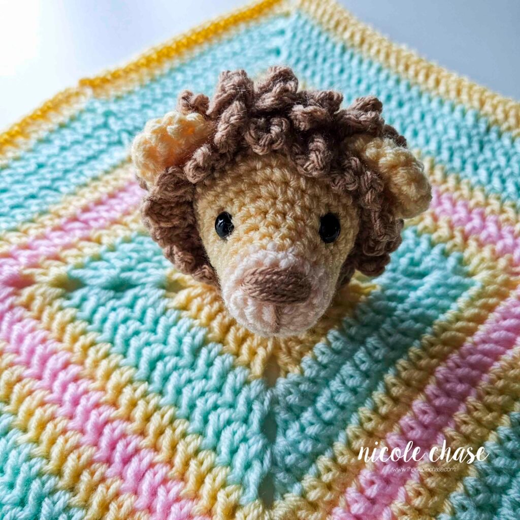 Attaching the head to the blanket of the crochet lion lovey pattern; placement before sewing.
