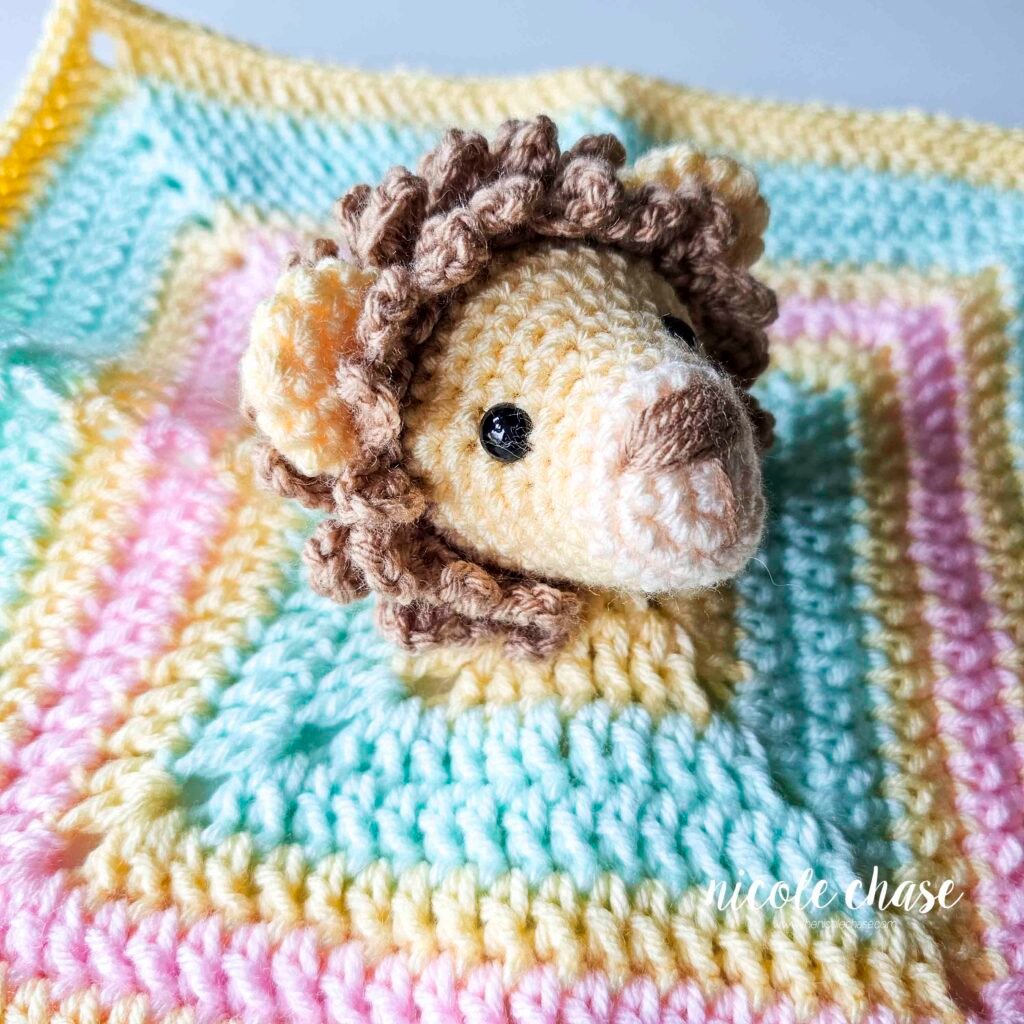 Proper placement of the crochet lion head onto the blanket for the lion lovey pattern, view 1.